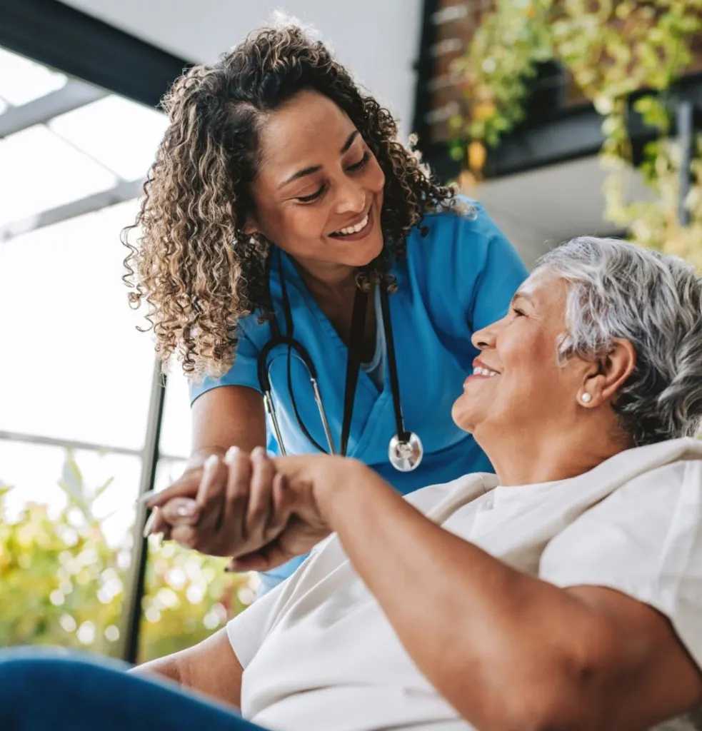 A nurse holding the hand of a smiling resident.